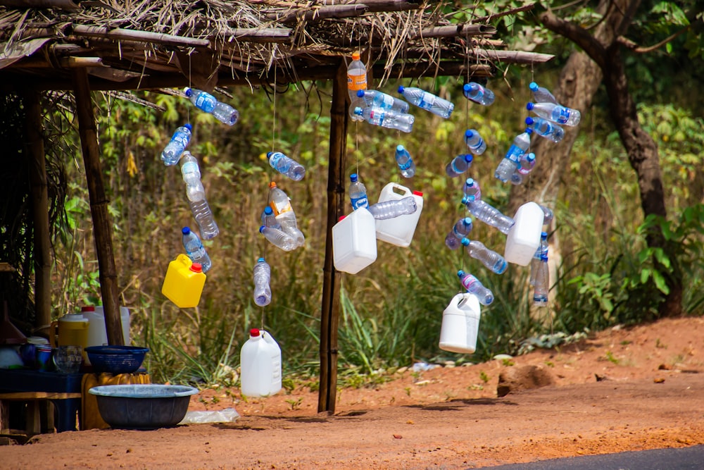 a bunch of plastic bottles hanging from a wooden pole