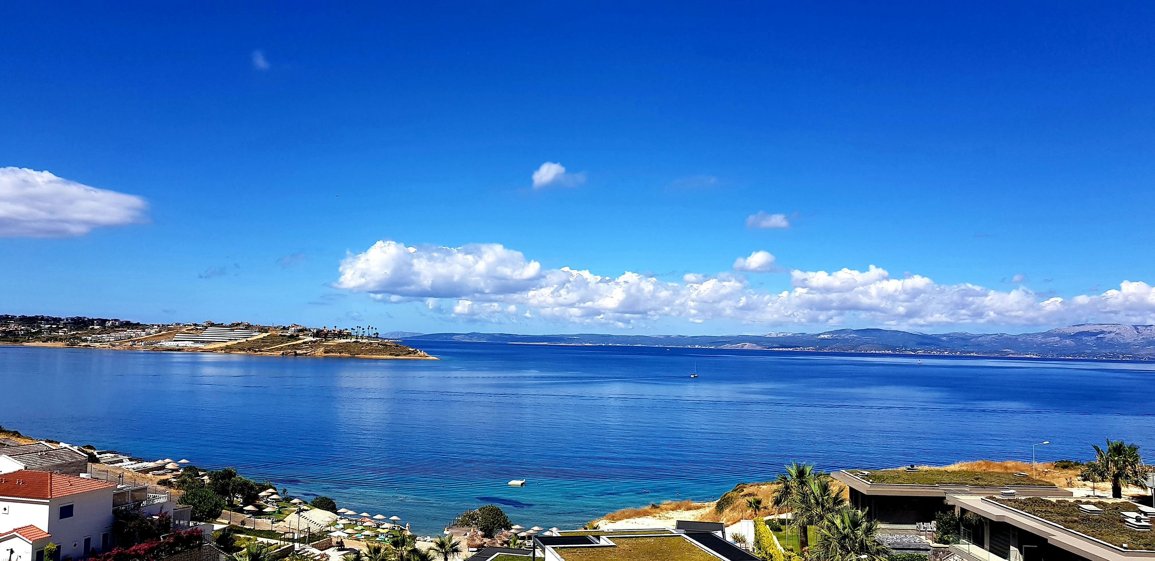 a large body of water sitting next to a lush green hillside