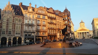 Golden hour light casting long shadows over a historic city square filled with locals.