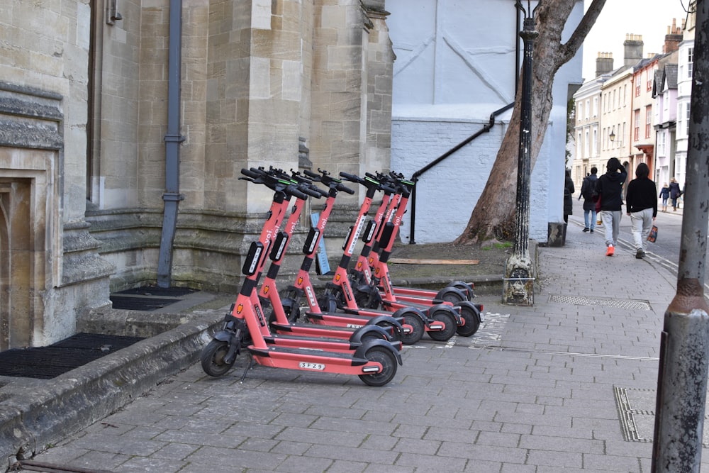 a row of red scooters parked on the side of a street
