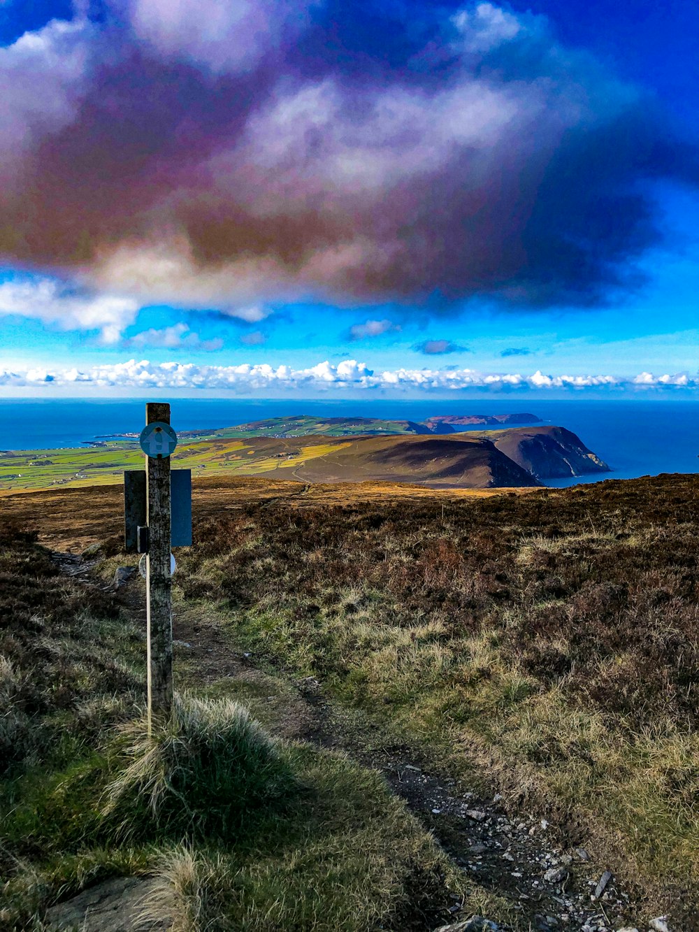 ein Schild auf einem grasbewachsenen Hügel mit Blick auf ein Gewässer