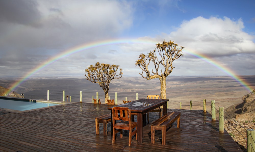 a wooden deck with a table and chairs under a rainbow