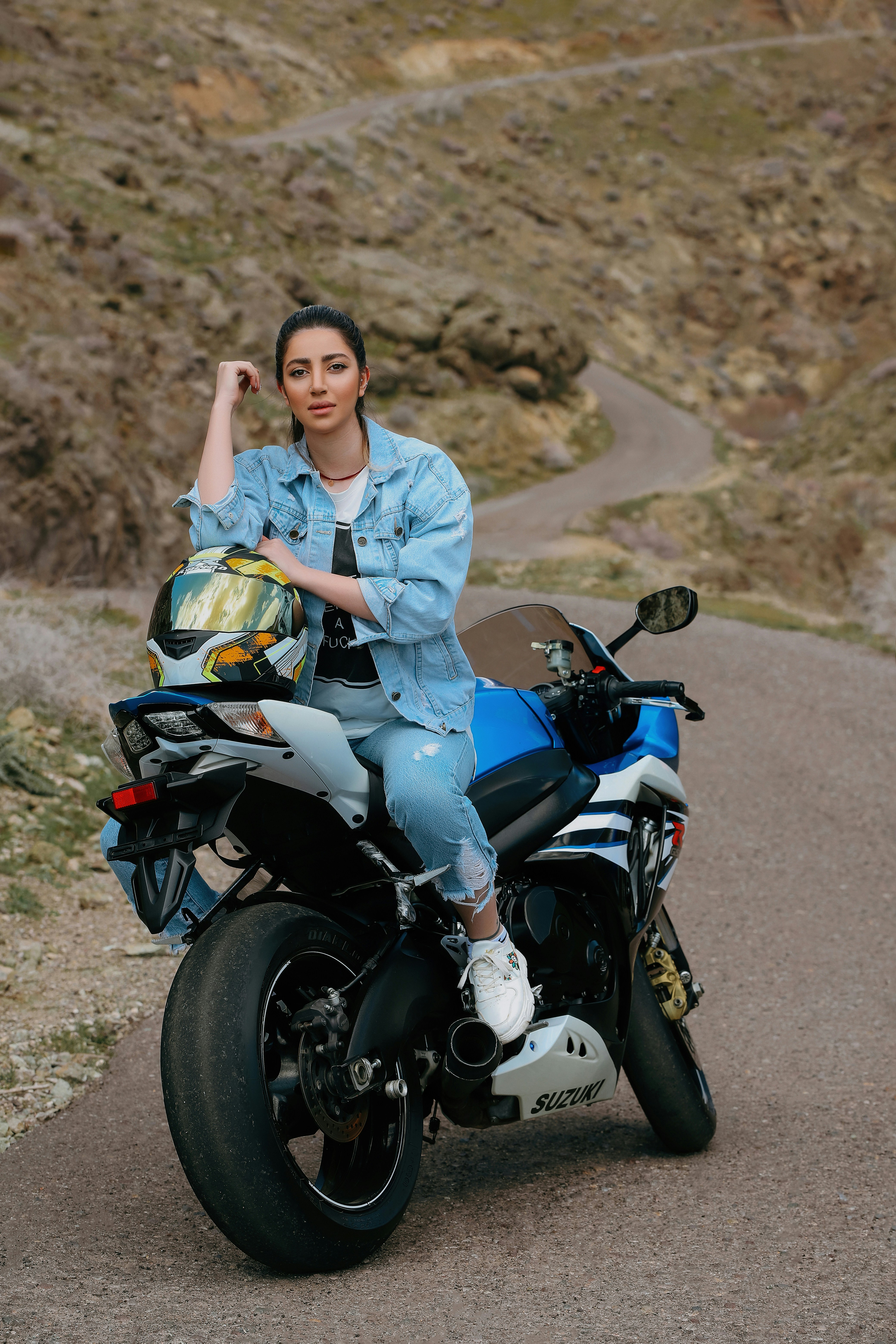 a woman sitting on a motorcycle on a road