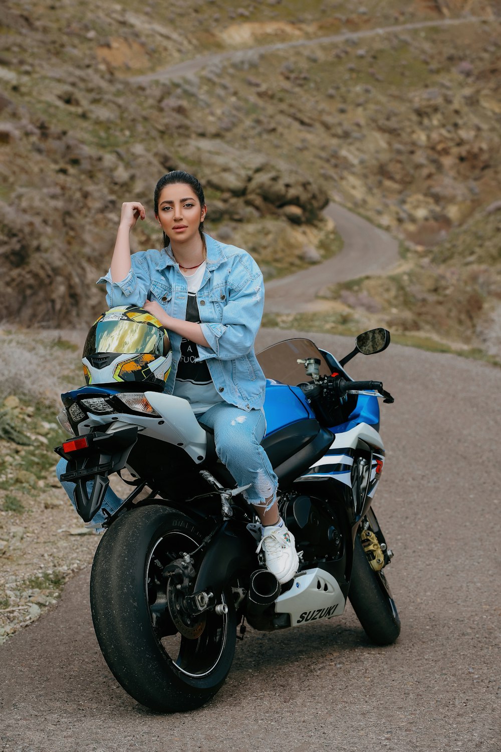 a woman sitting on a motorcycle on a road