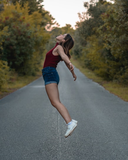a woman jumping in the air on a road