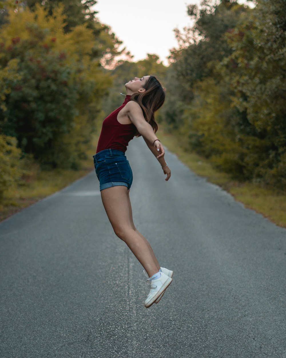a woman jumping in the air on a road