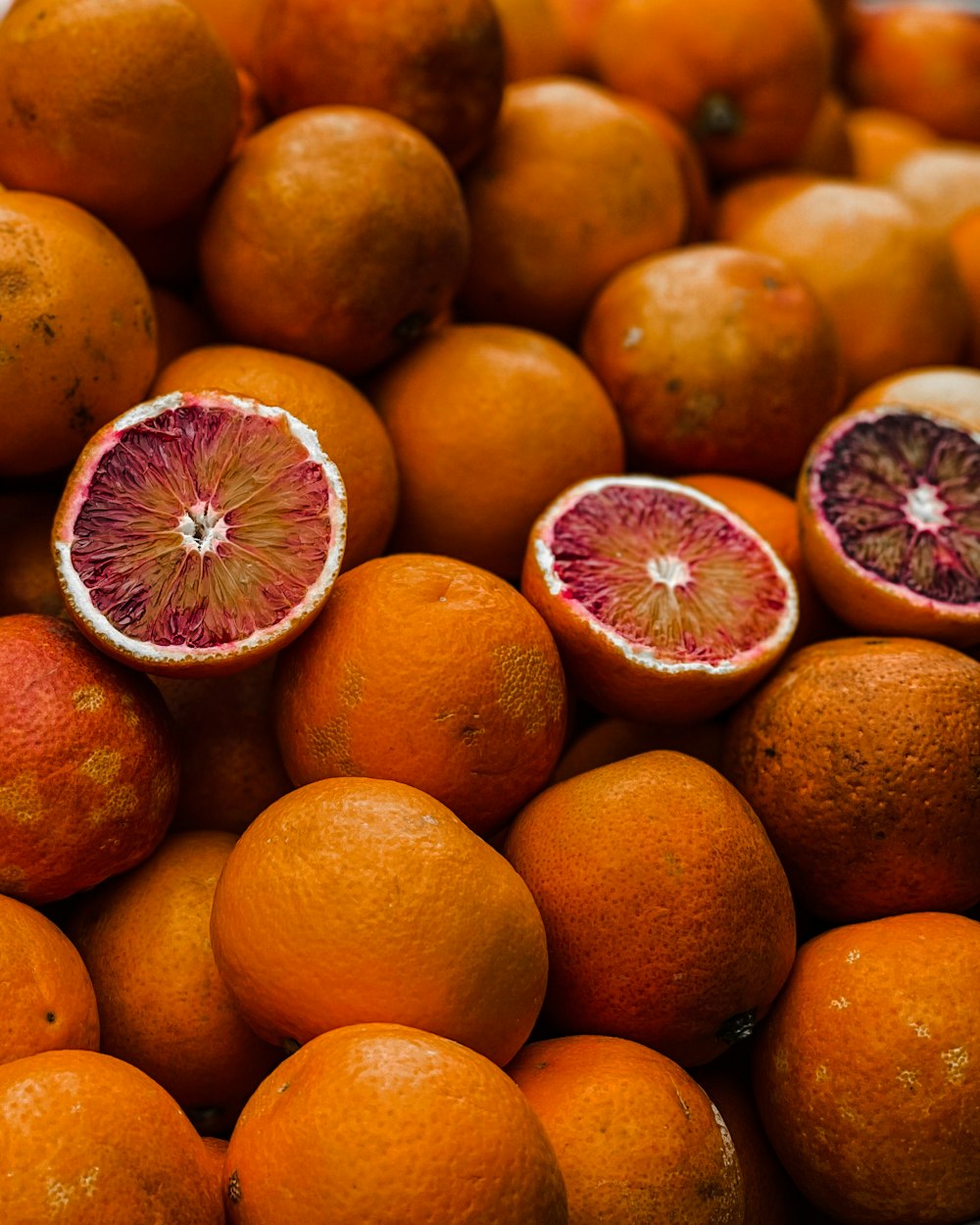 a pile of oranges with one cut in half