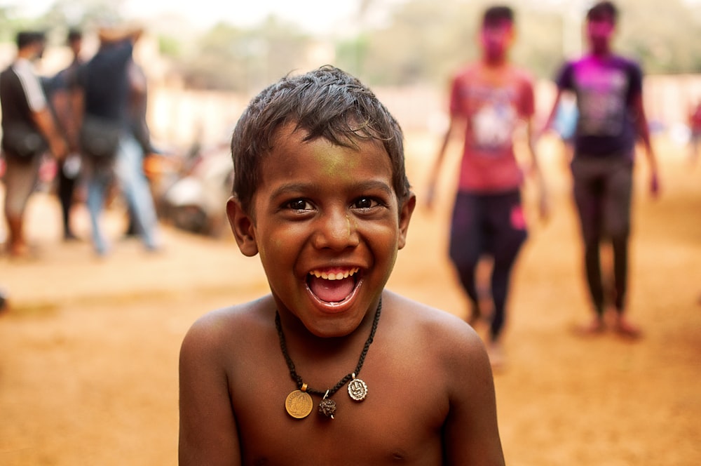 a young boy smiles as he stands in front of a group of people