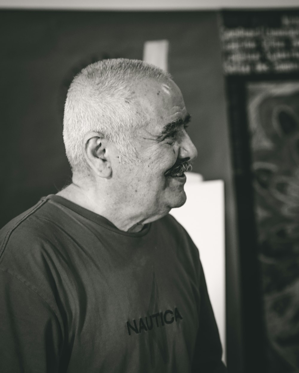 Ein Mann mit Schnurrbart steht vor einem Gemälde