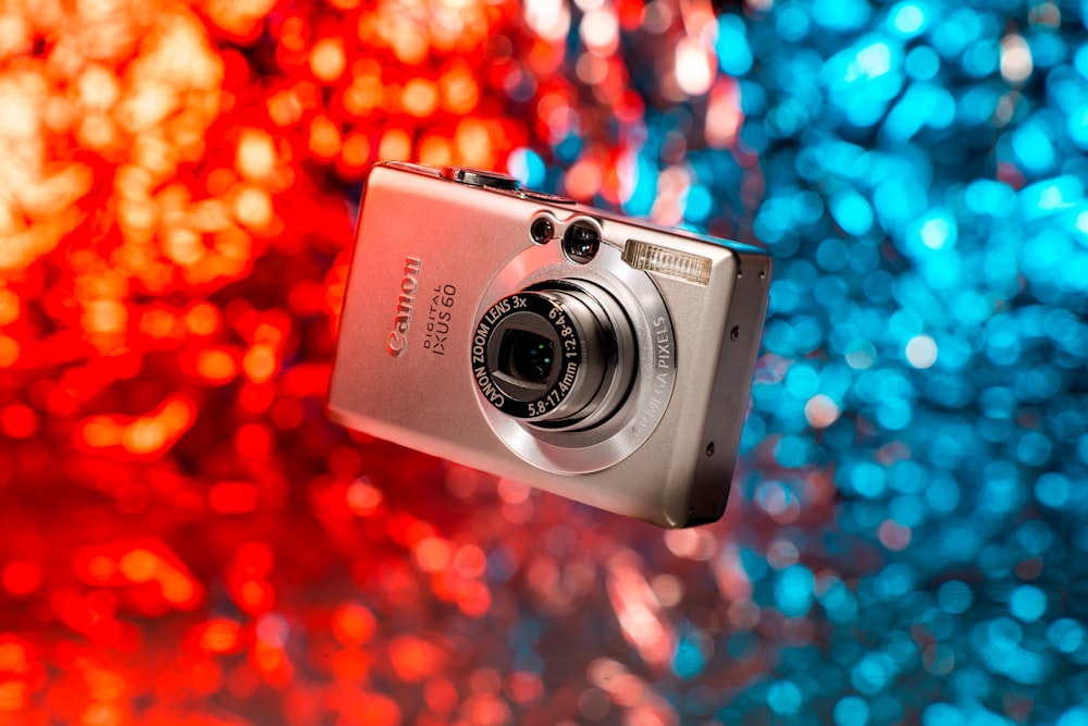 Una fotocamera digitale viene mostrata di fronte a uno sfondo colorato