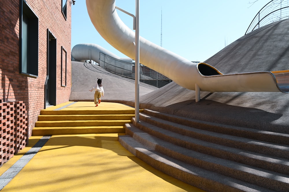 a person standing on a yellow carpeted walkway next to a slide