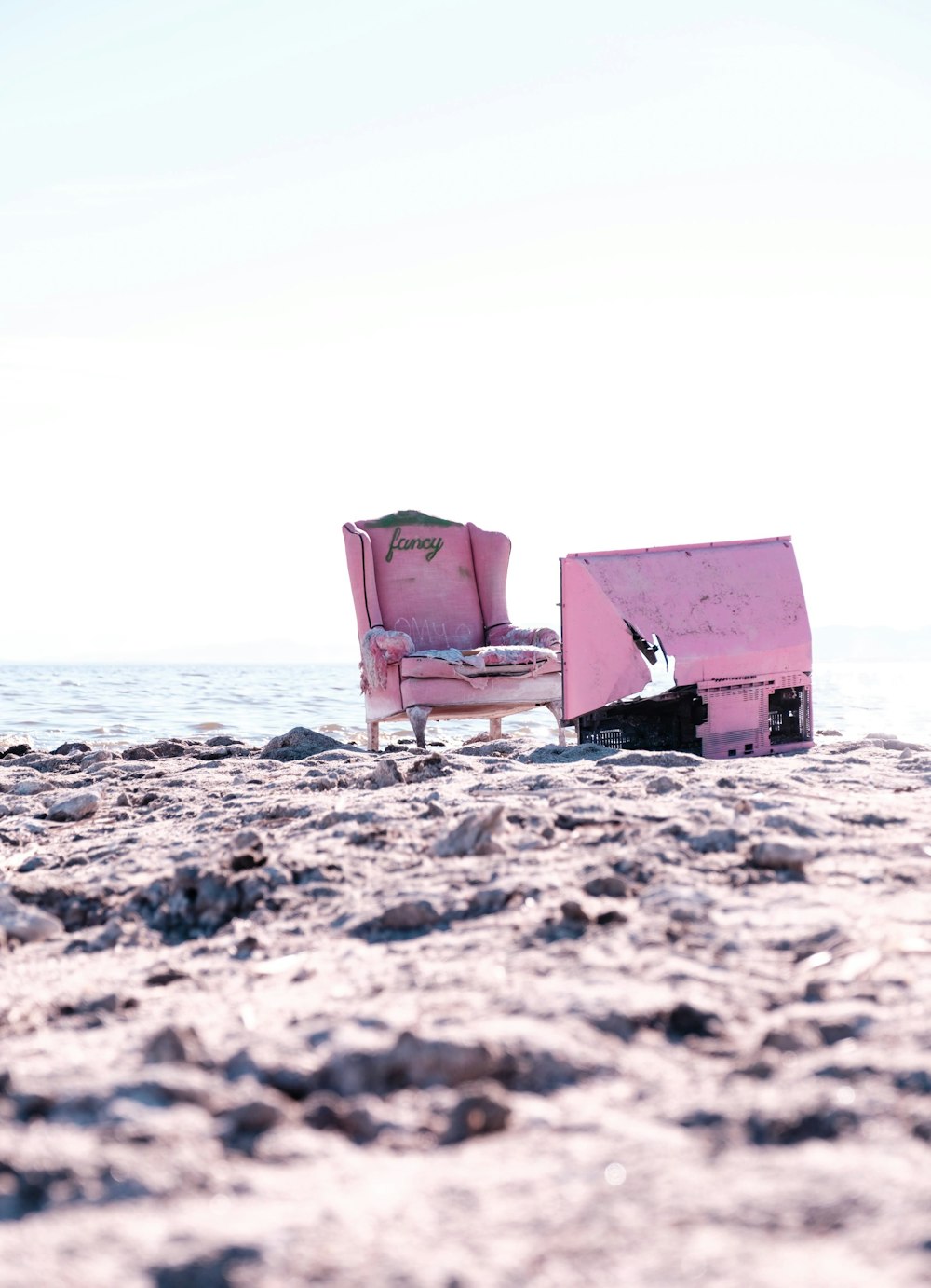 Ein rosa Stuhl sitzt auf einem Sandstrand