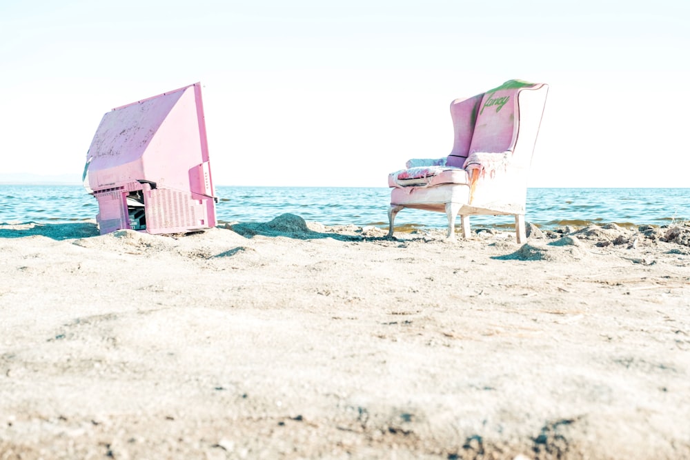 a couple of chairs sitting on top of a sandy beach