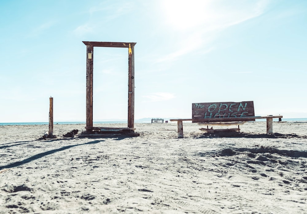 a wooden bench sitting on top of a sandy beach