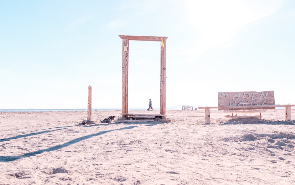 a wooden bench sitting on top of a sandy beach