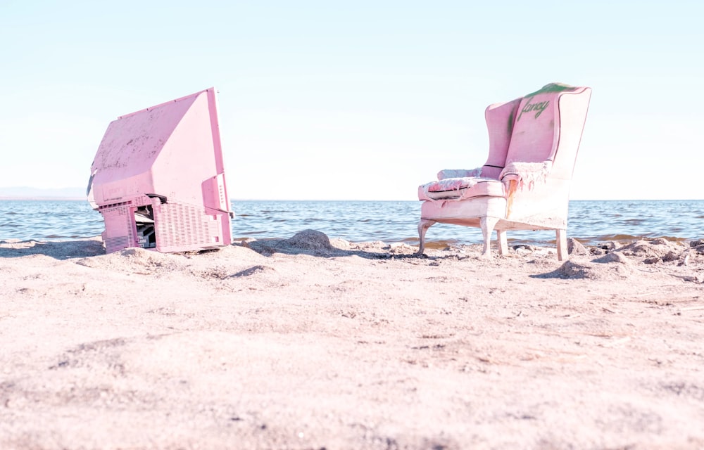 a pink chair sitting on top of a sandy beach
