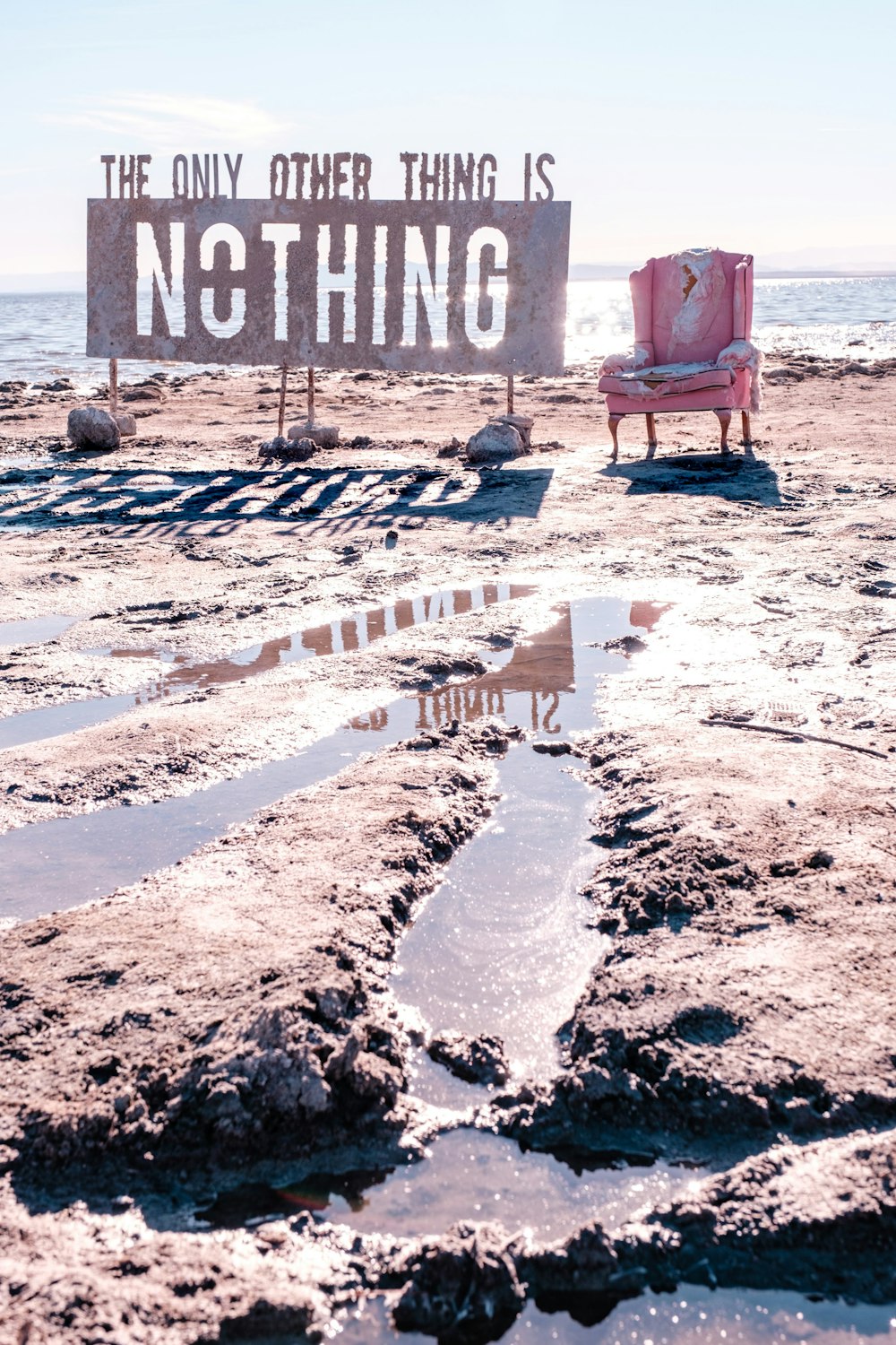 a chair sitting on top of a sandy beach next to the ocean