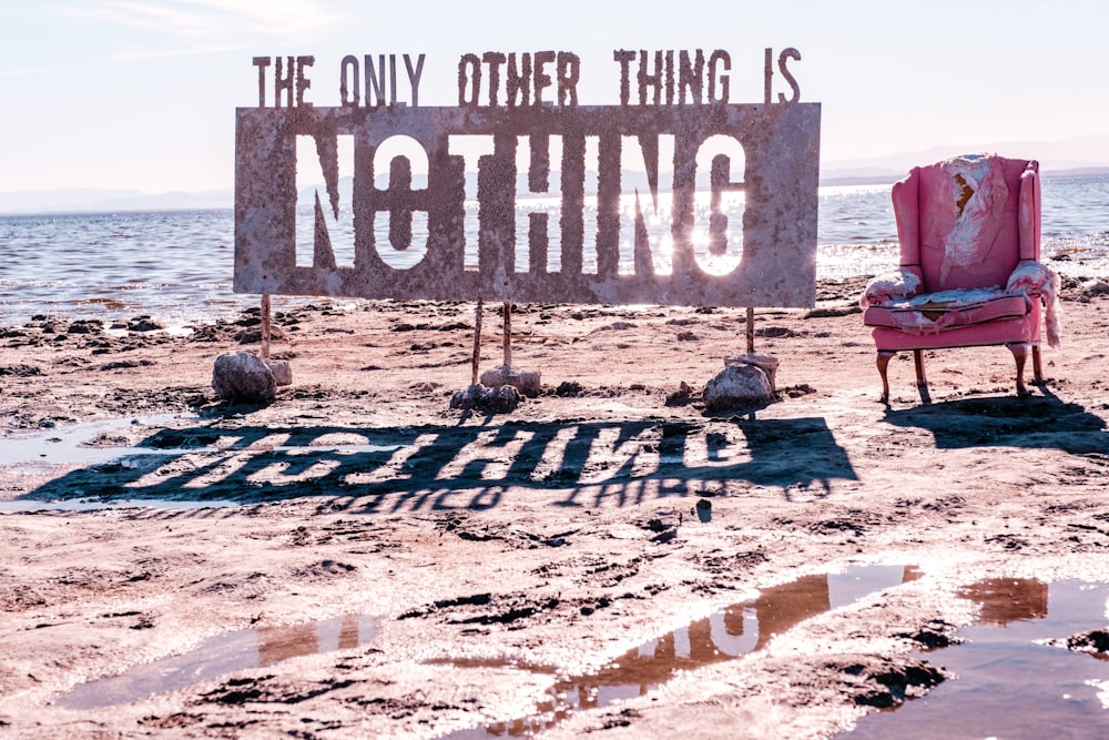 a pink chair sitting on top of a sandy beach