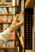 a person holding a piece of paper in front of a book shelf
