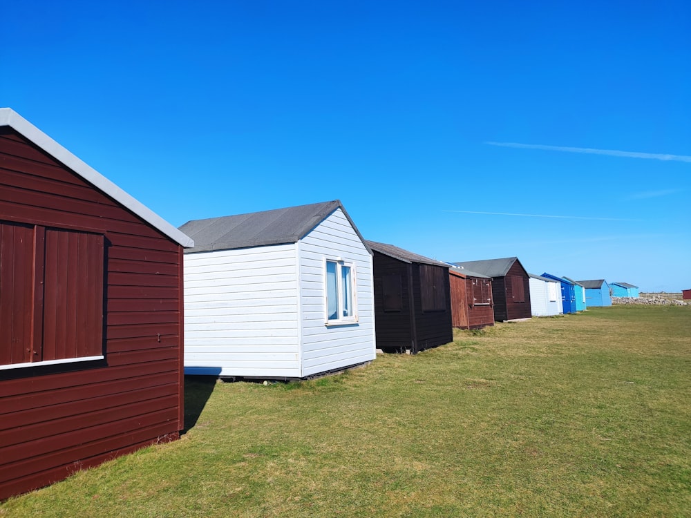 a row of houses sitting on top of a grass covered field