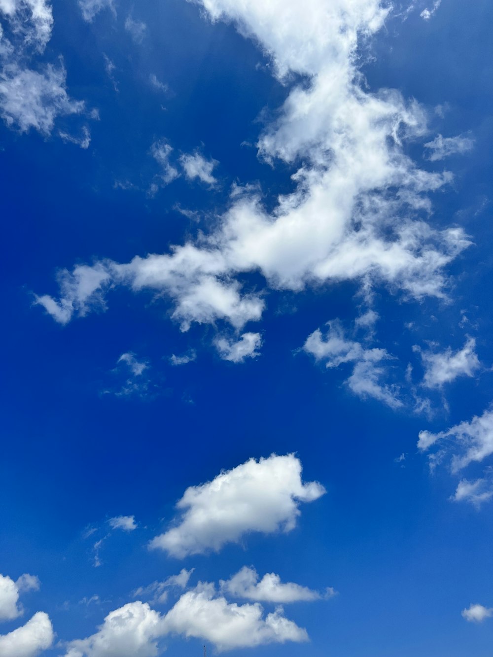 a blue sky with white clouds and a plane in the foreground