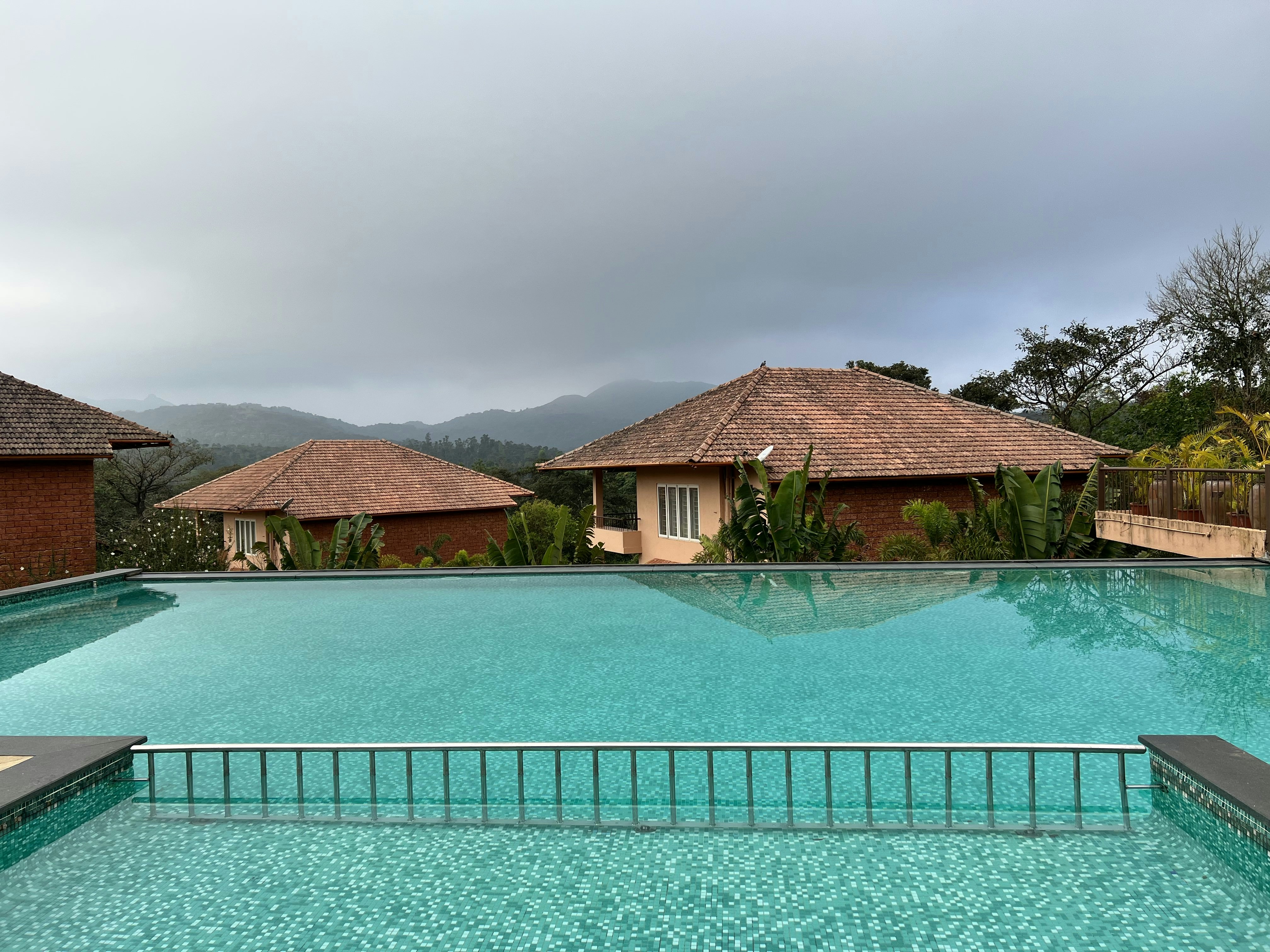 a large swimming pool next to a lush green hillside