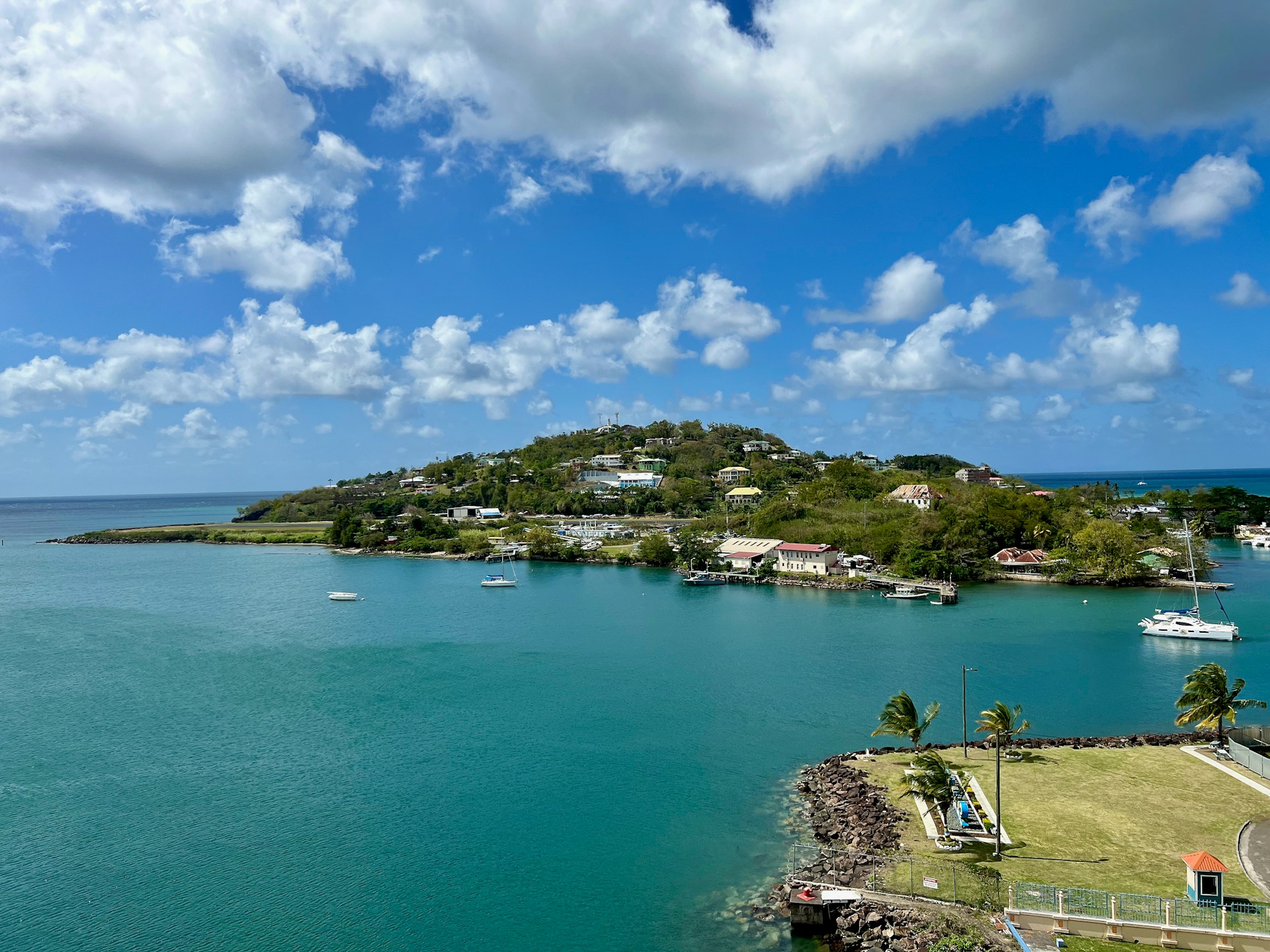 a small island surrounded by blue water and clouds