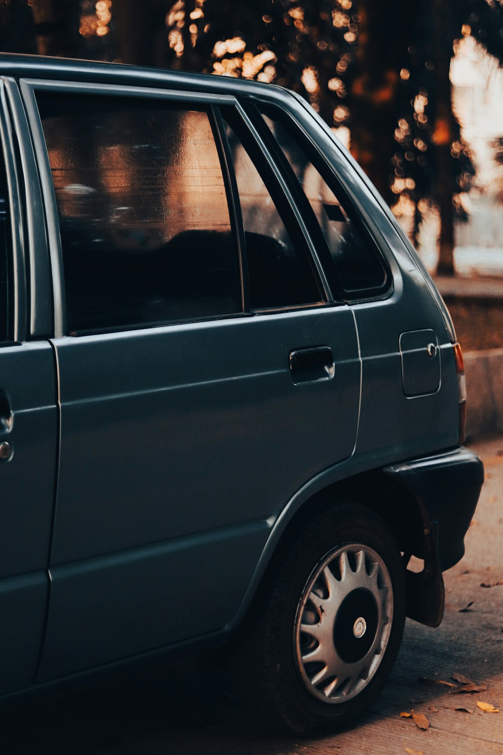 a small blue car parked on the side of the road