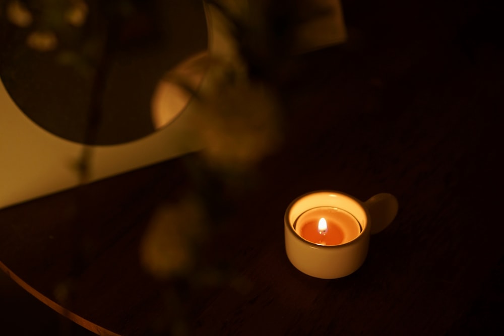 uma vela acesa sentada em cima de uma mesa de madeira