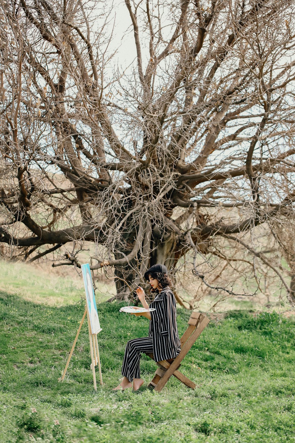 a woman sitting on a chair next to a easel