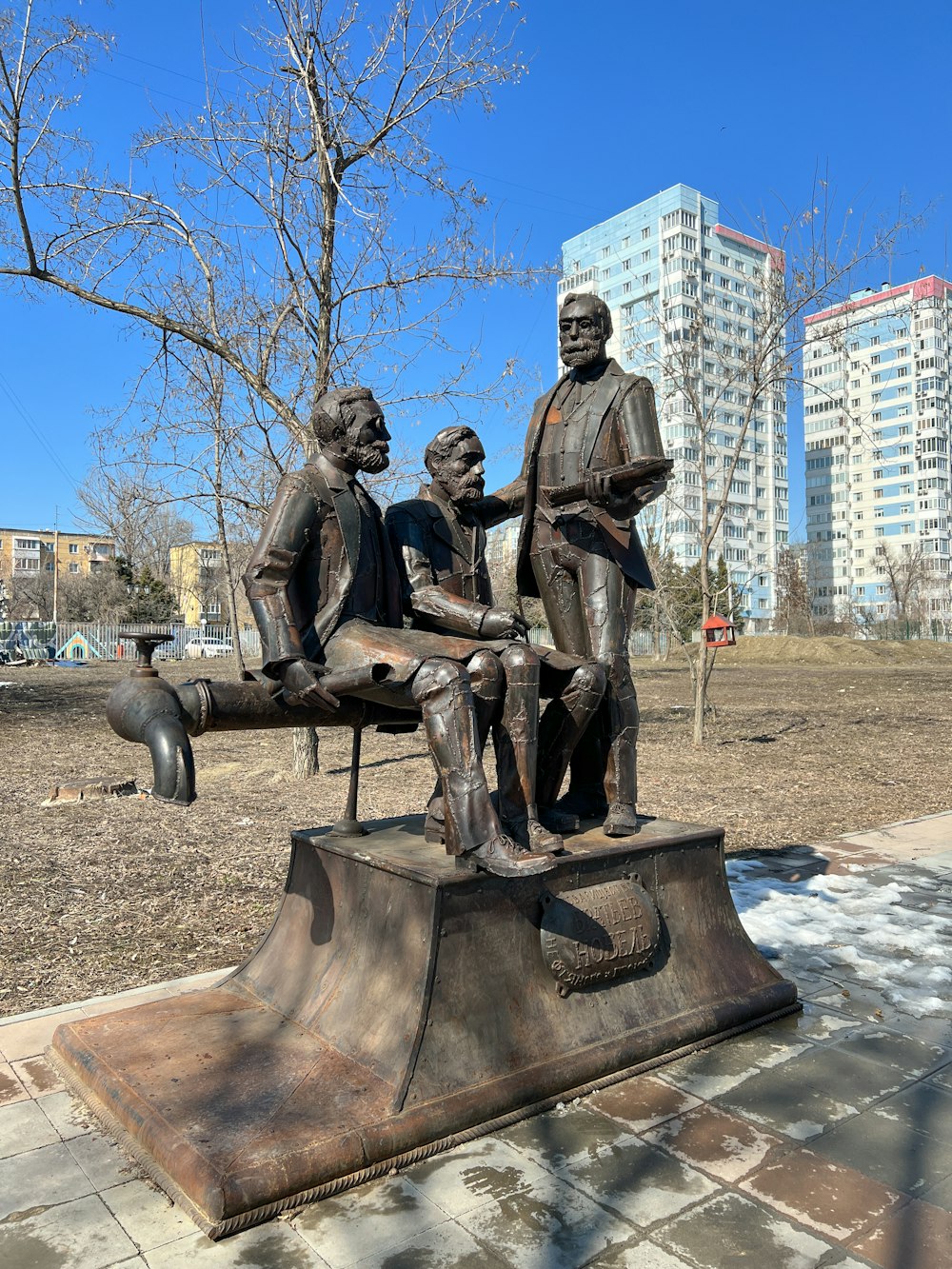 Eine Statue von drei Personen, die auf einer Bank sitzen