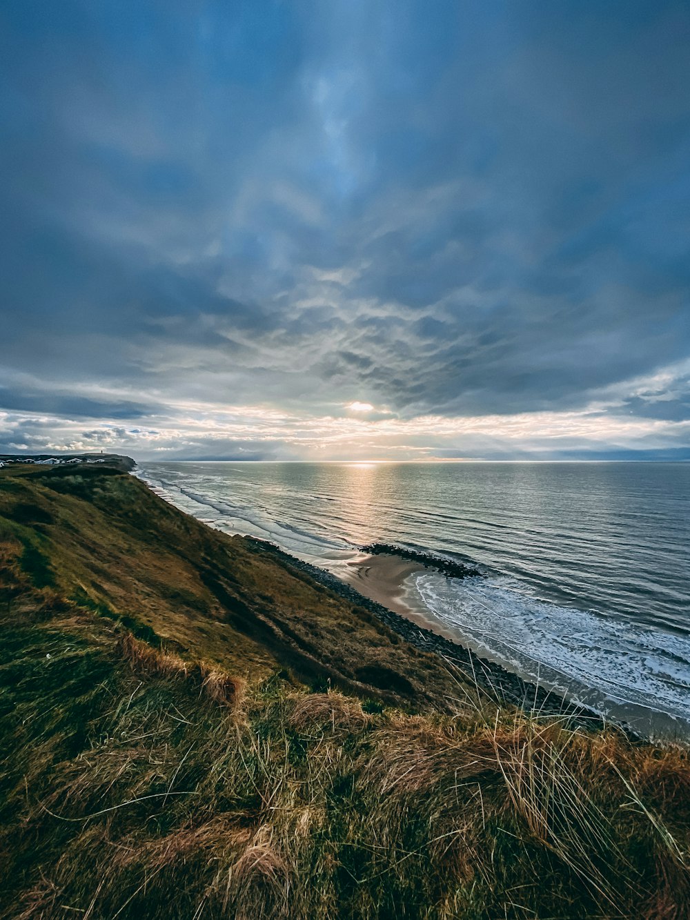 the sun is setting over the ocean on a cloudy day