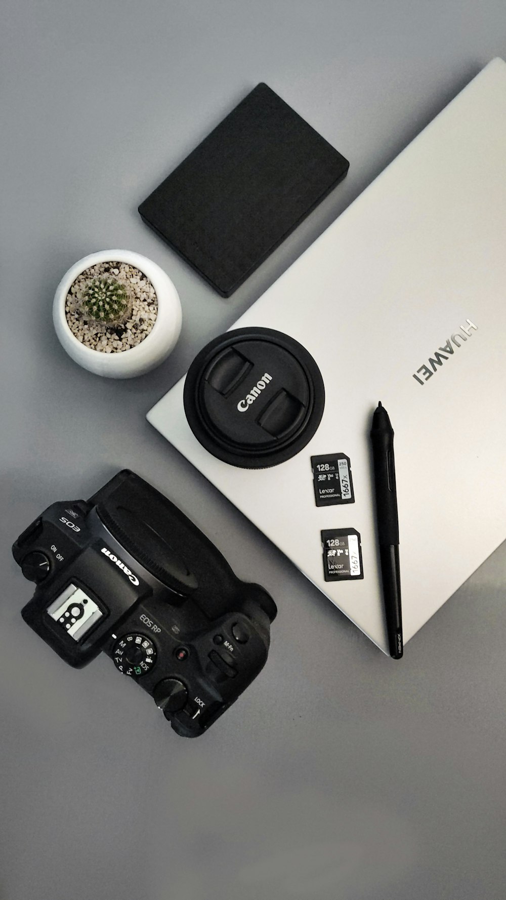 a camera, a bowl of flowers, a pen, and a laptop on a