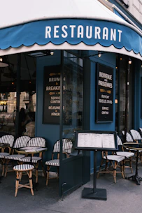 the outside of a restaurant with tables and chairs