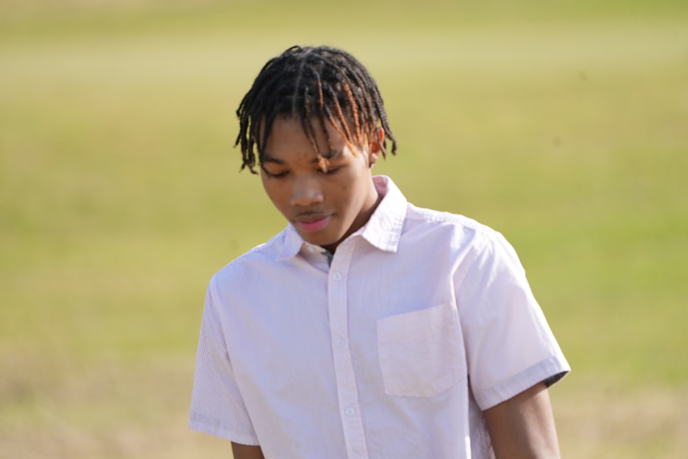 a young man with dreadlocks standing in a field