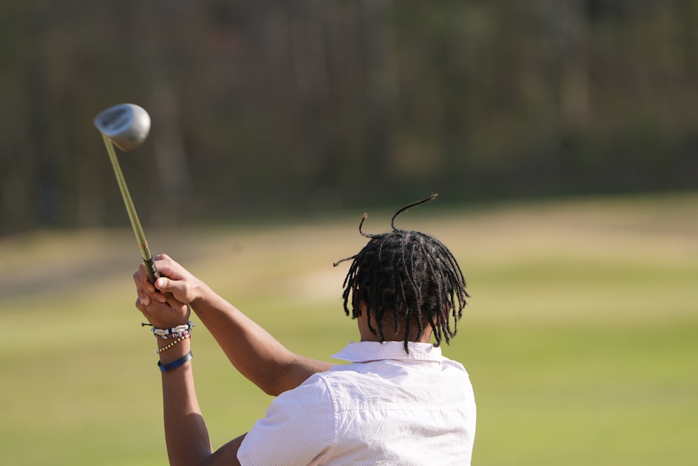 a man with dreadlocks swinging a golf club