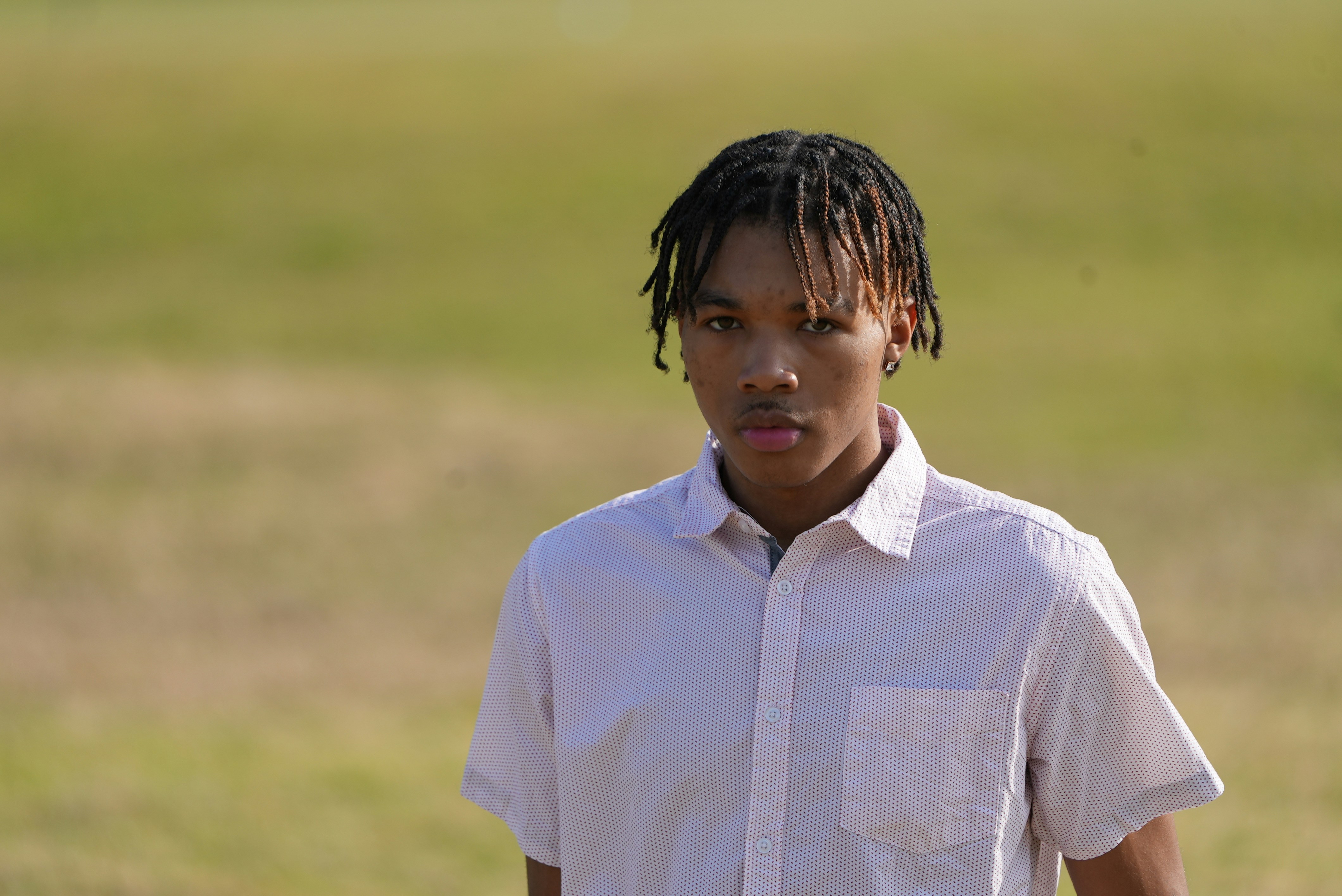 a young man with dreadlocks standing in a field
