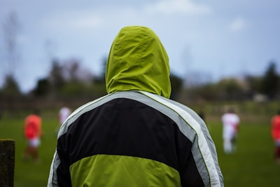 A scout observing a match from the stands with notes in hand.