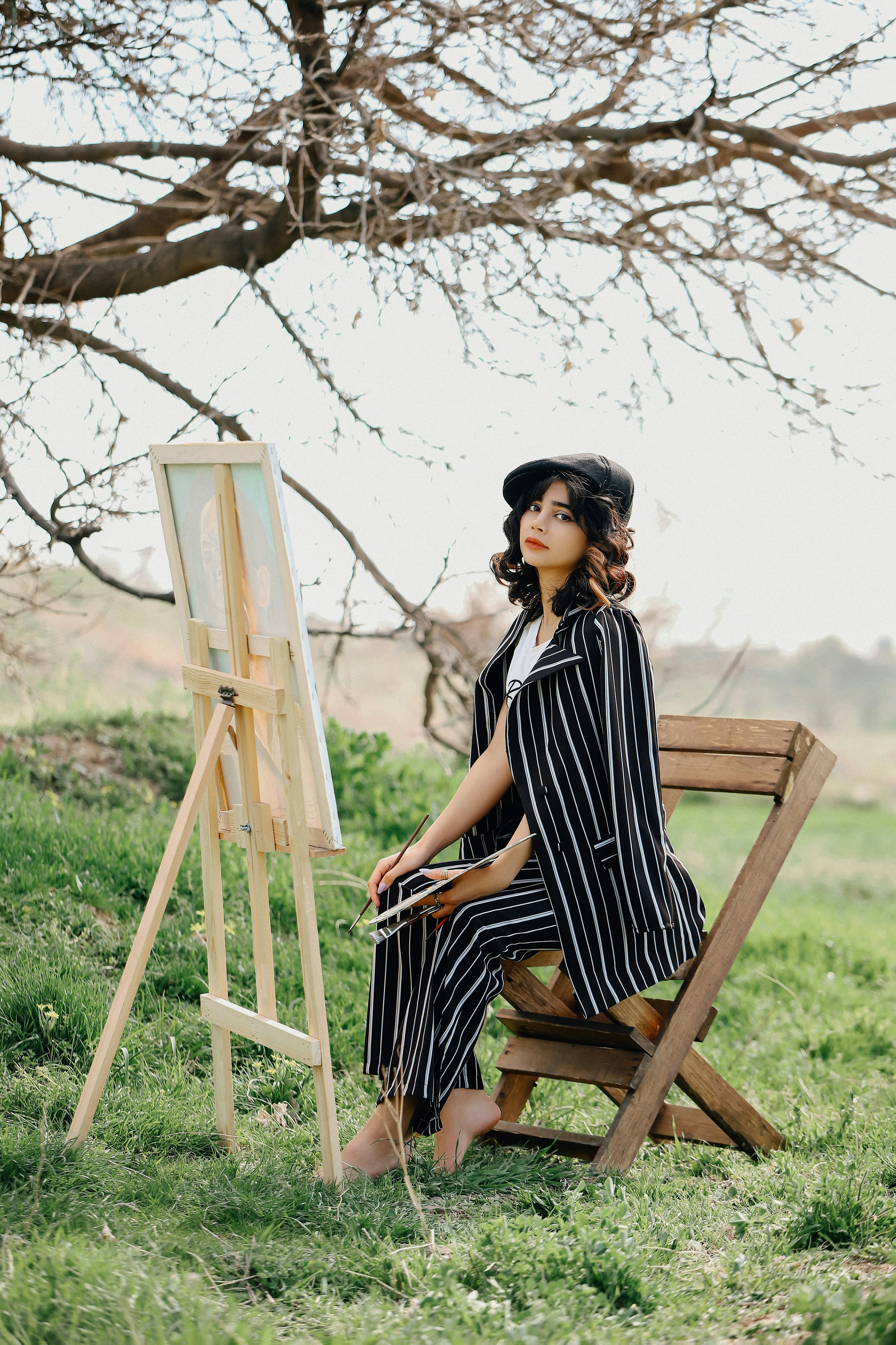 a woman sitting in a chair next to a easel