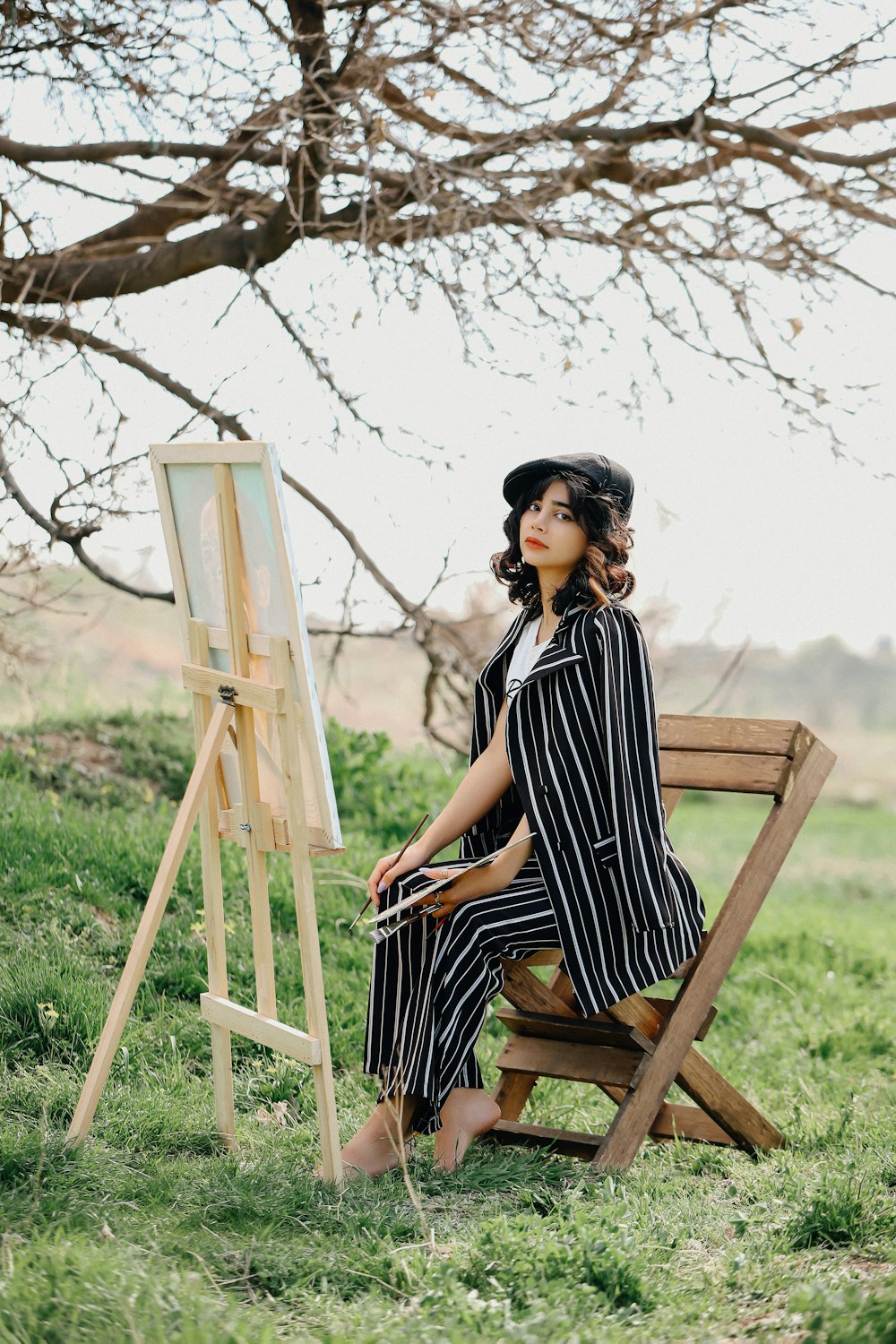 a woman sitting in a chair next to a easel