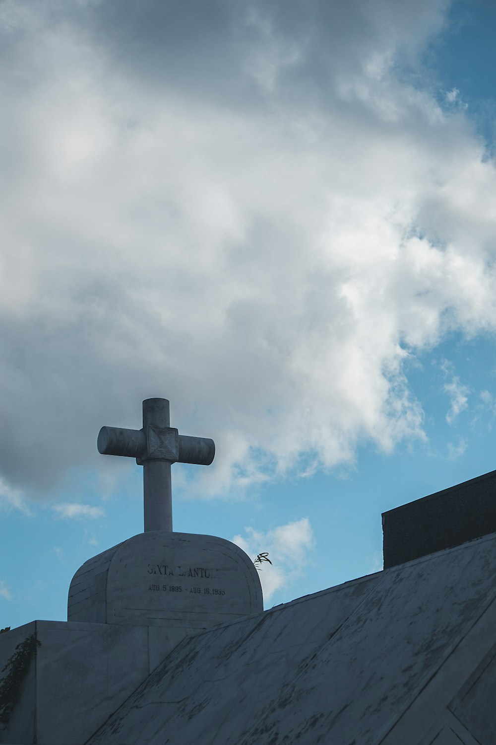 a cross on top of a building with a sky background