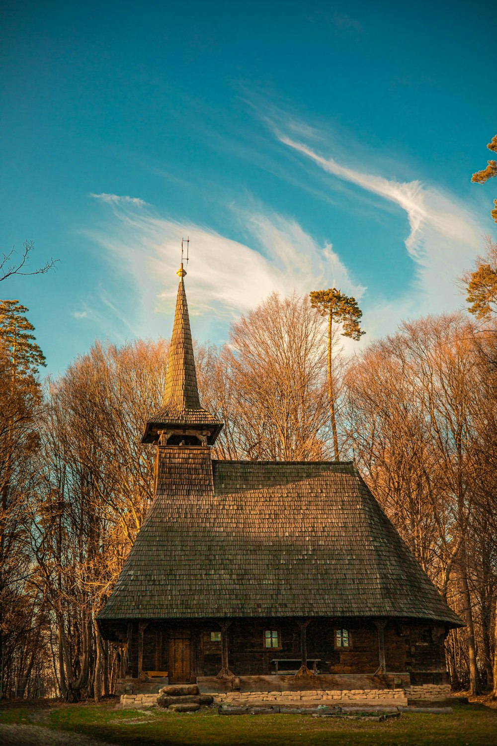 an old wooden church with a steeple surrounded by trees