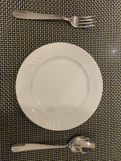 A hand placing a copper fork beside a matching copper dinner plate.