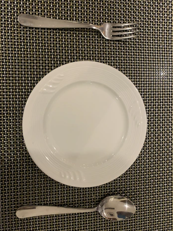 A hand placing a copper fork beside a matching copper dinner plate.
