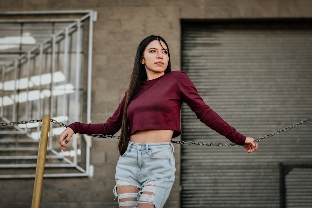 a woman with long hair wearing ripped jeans and a crop top