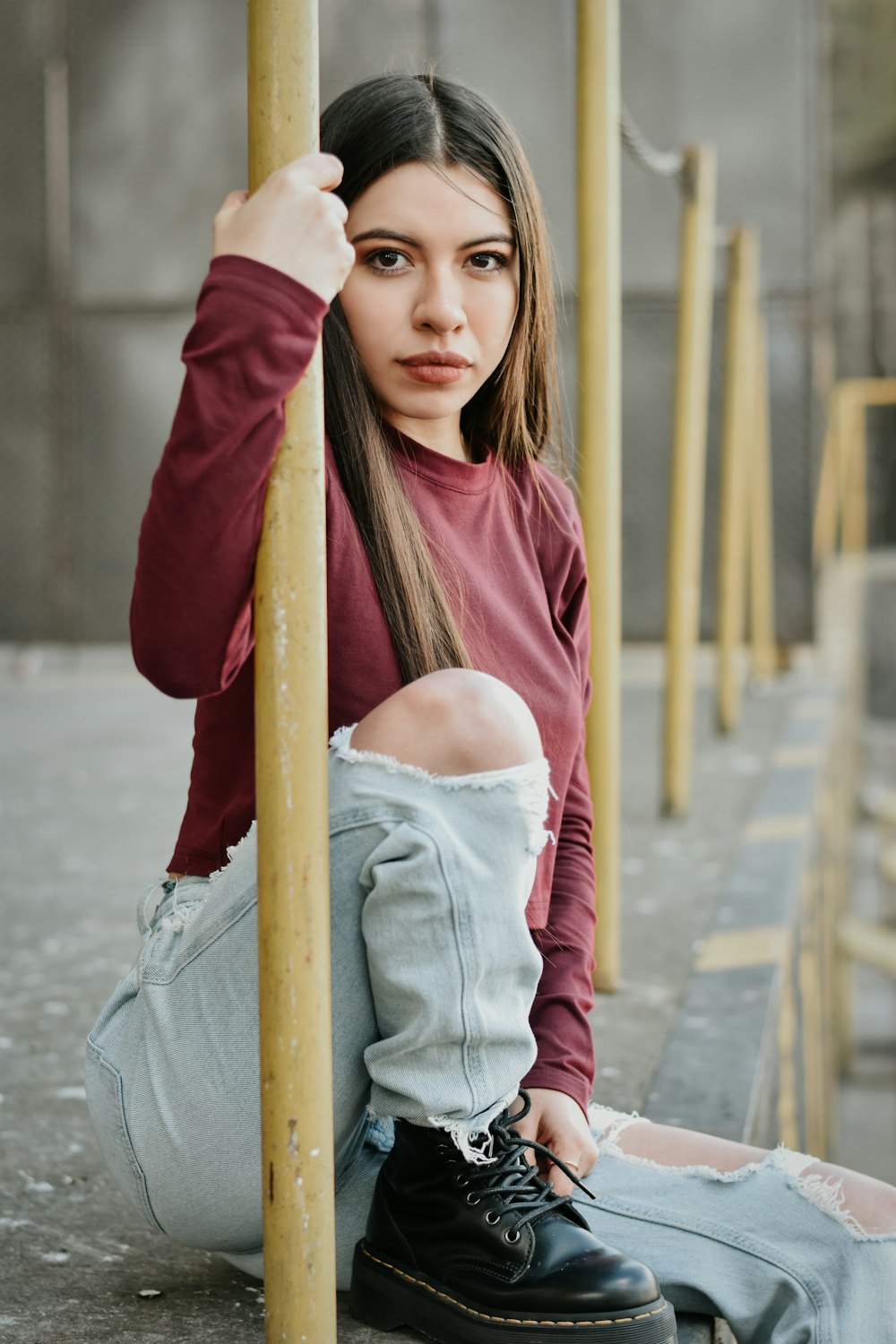 a woman sitting on the ground next to a pole