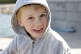 a young boy wearing a gray hoodie and smiling