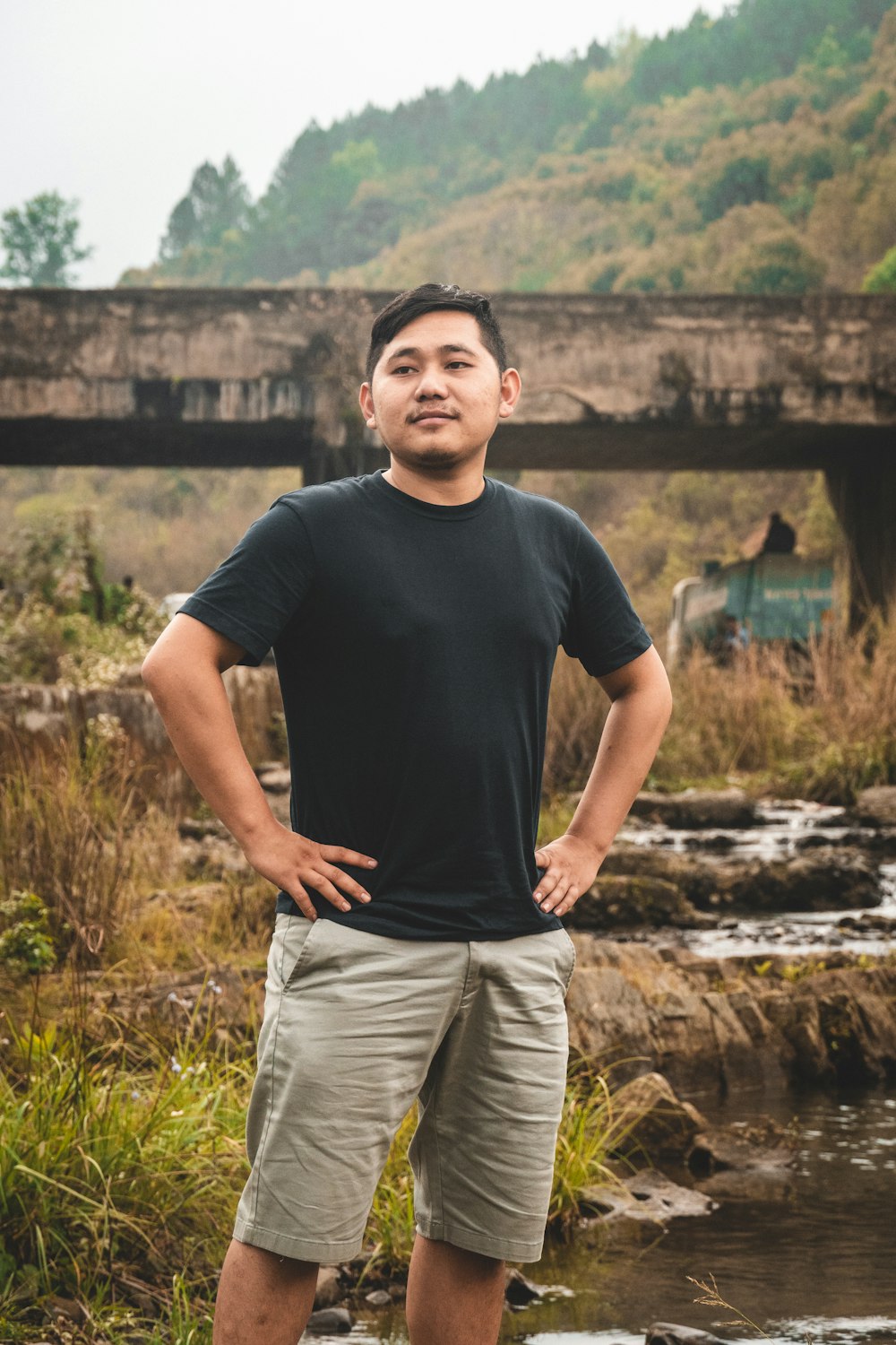 a man standing in front of a river with his hands on his hips