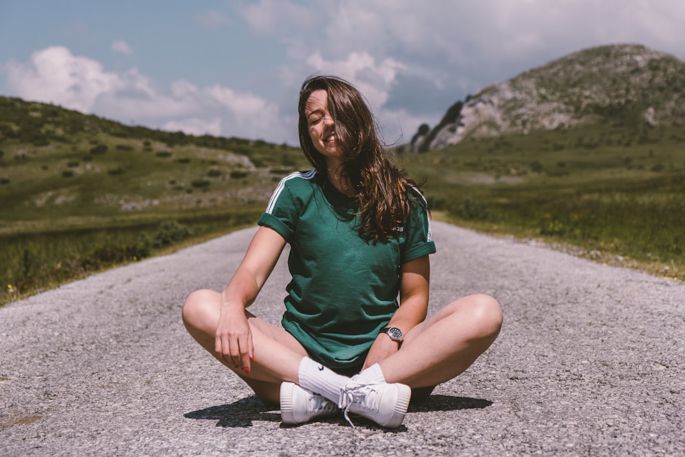 a woman sitting in the middle of a road