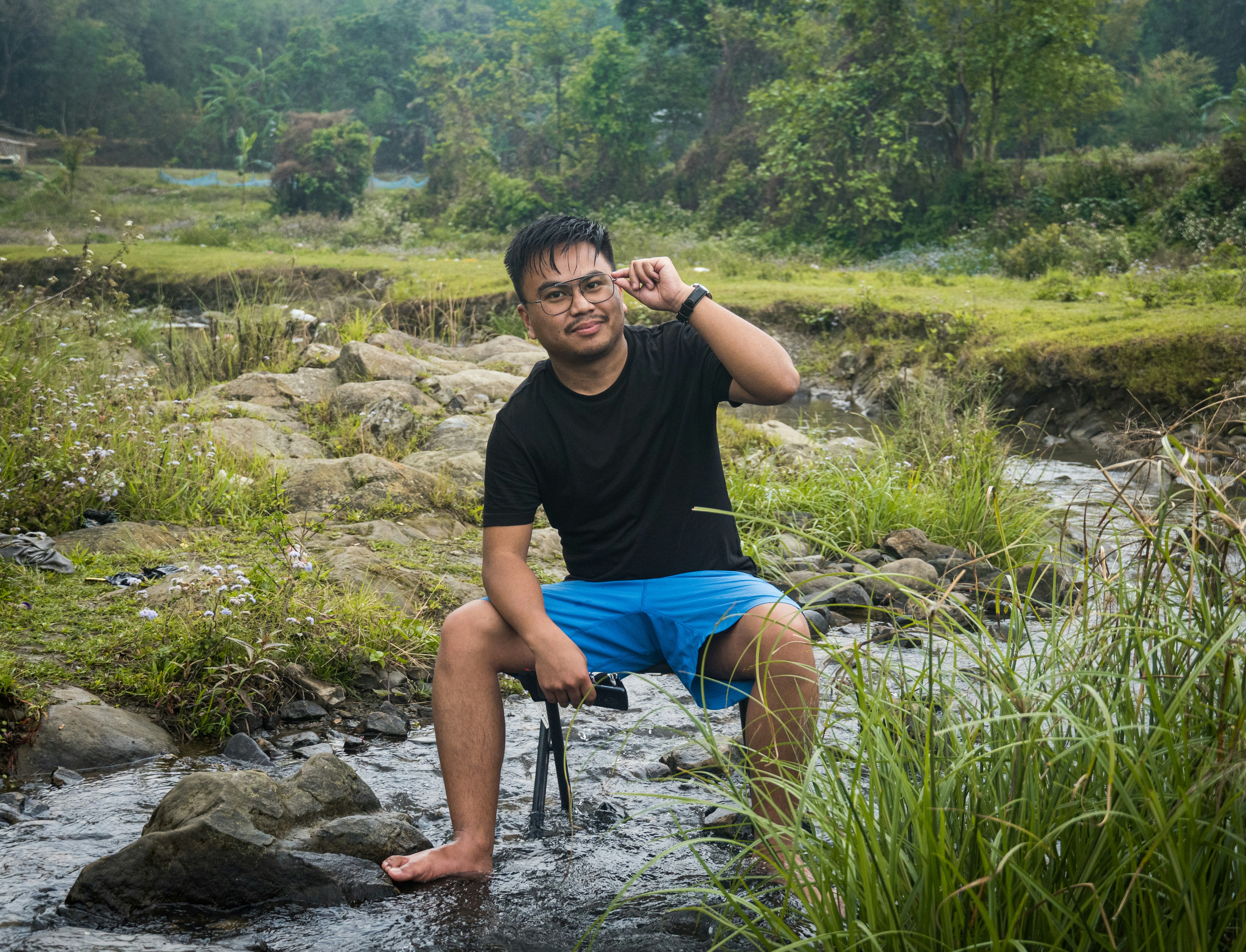 Seorang pria duduk di atas batu di sungai